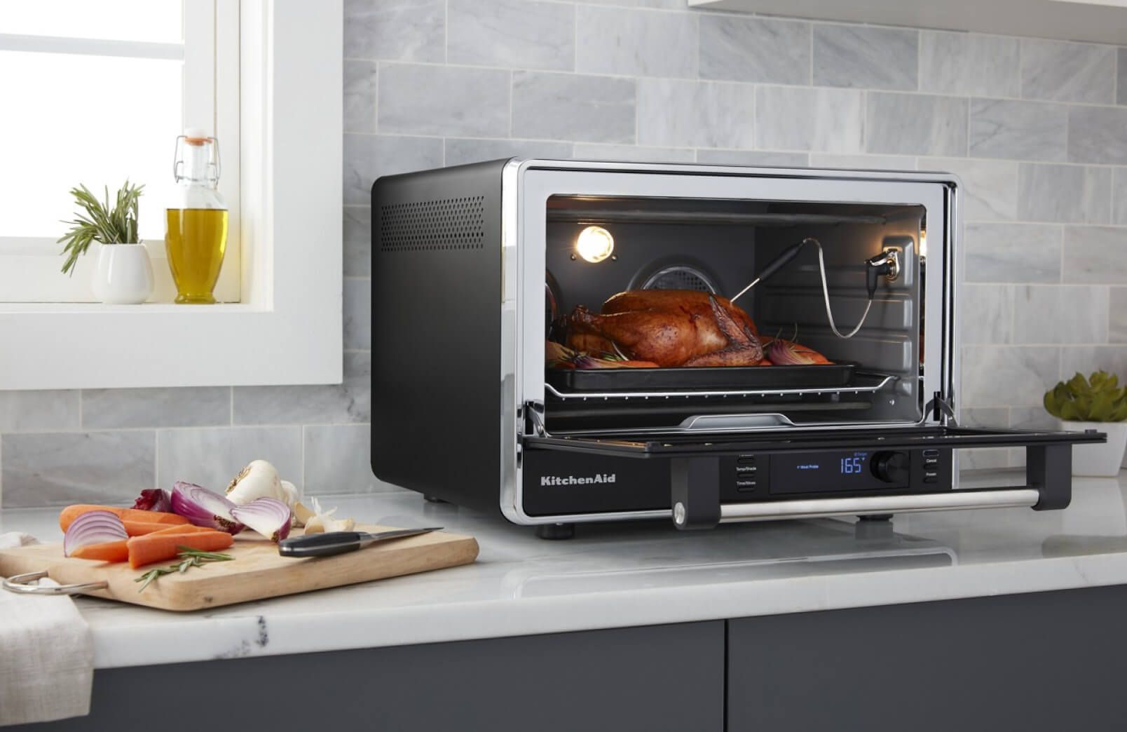 A KitchenAid® Dual Convection Countertop Oven roasting a whole chicken.